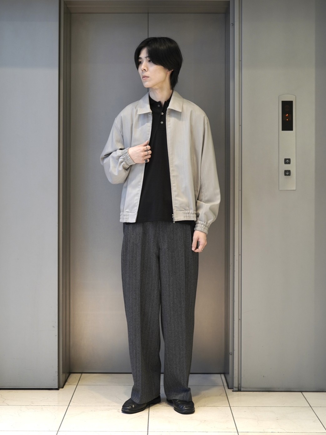 ライトカラーのブルゾンと黒のポロニット、ワイドパンツを合わせた全身スタイリング